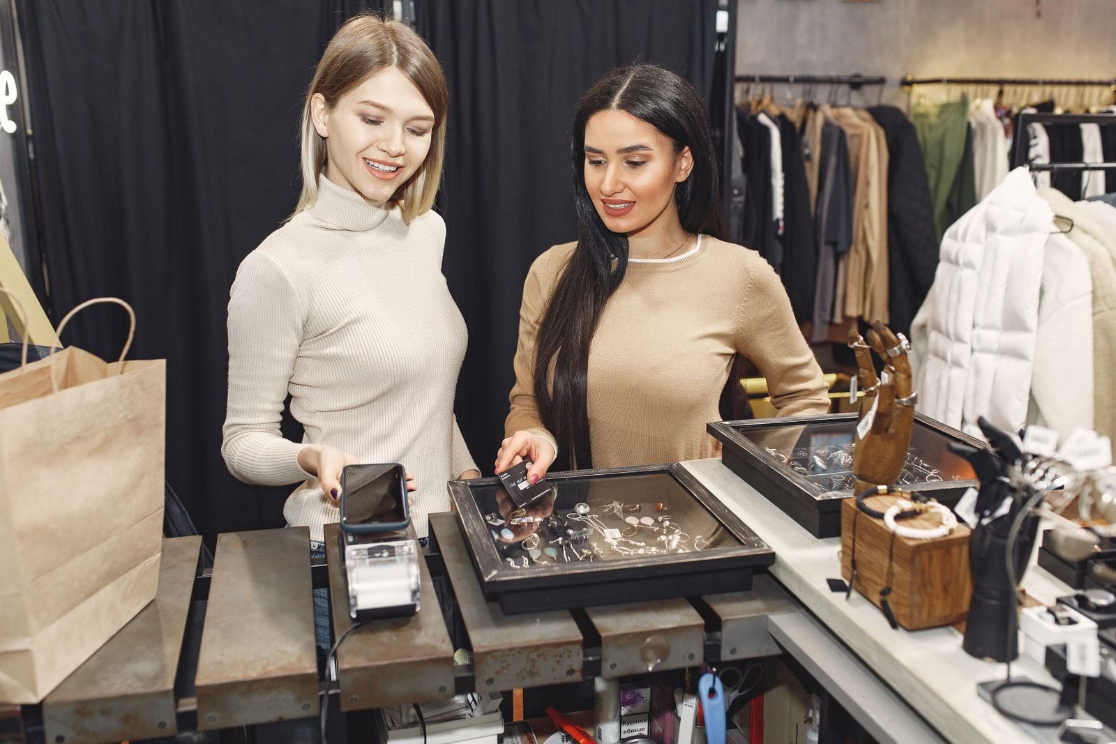 Customers making a contactless payment with a smartphone at a retail counter.