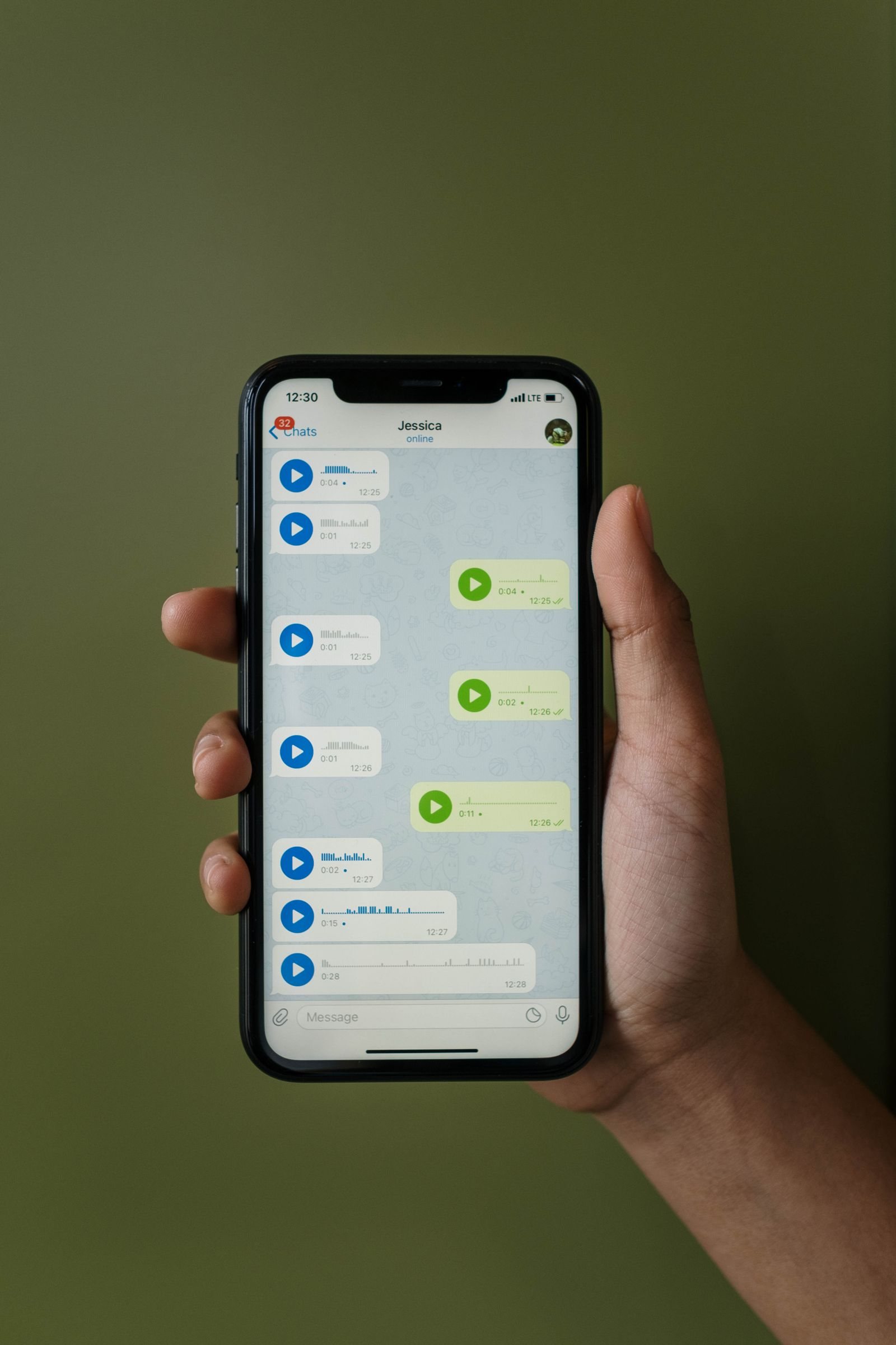 A hand holds a smartphone showing a mobile messaging interface.