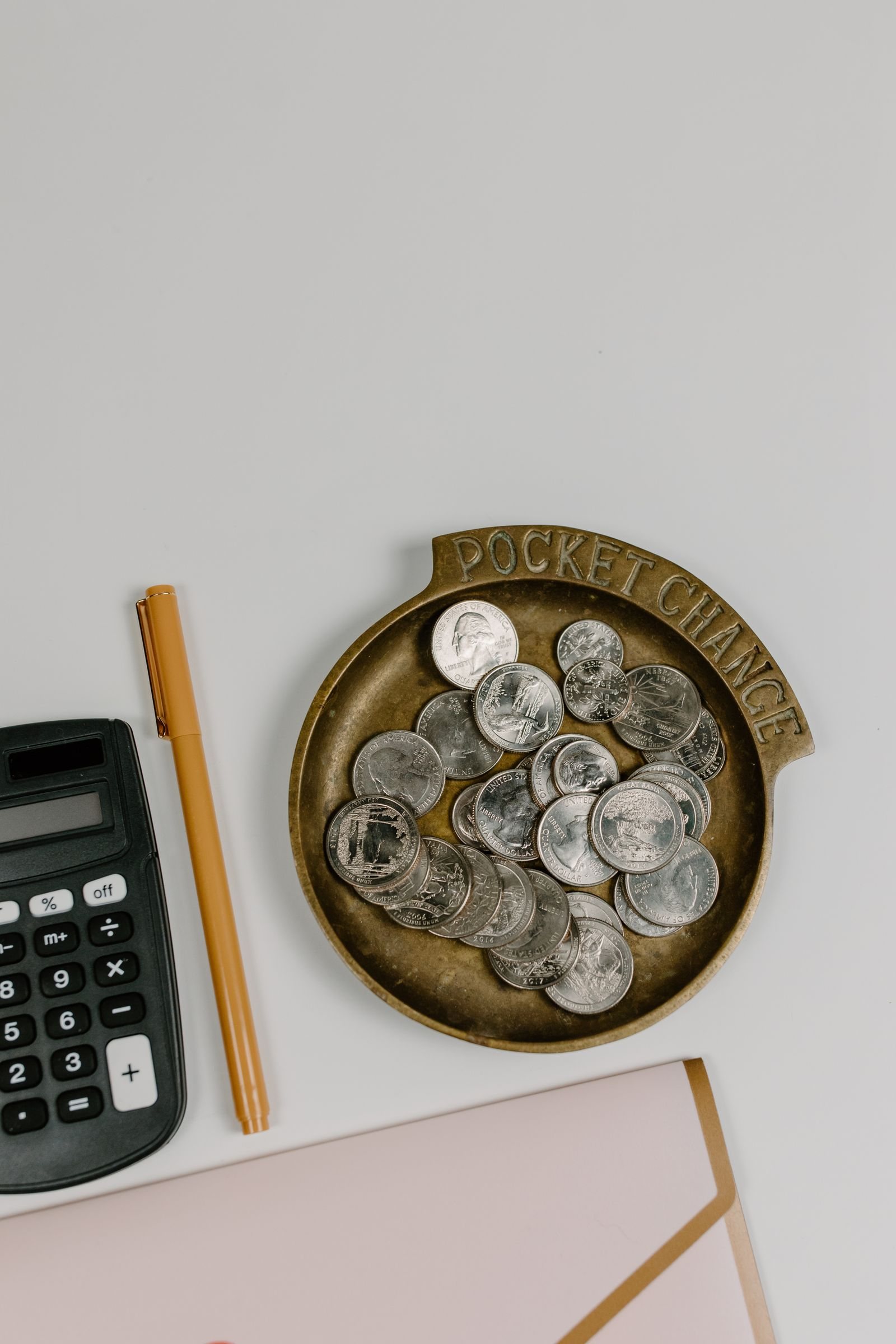Coins, a calculator and a pen on a desk for comparing loyalty reward values.