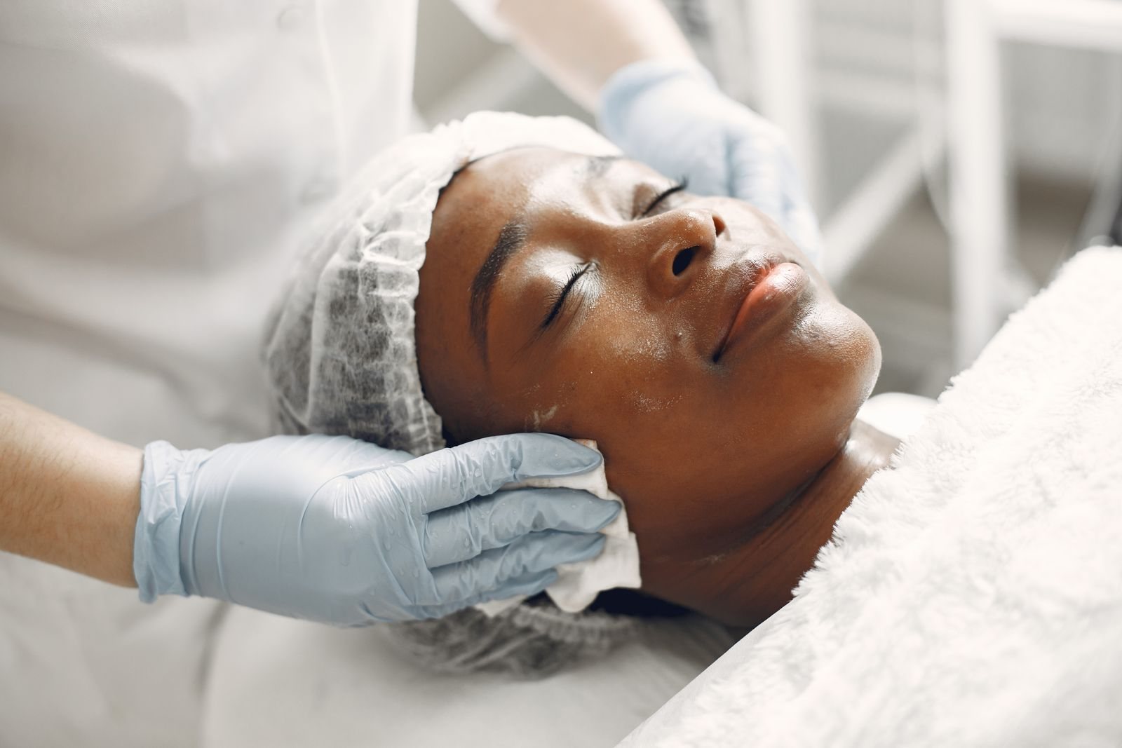 An aesthetician providing a gentle facial treatment to a spa client.